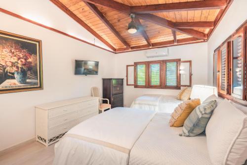 a bedroom with two beds and a wooden ceiling at Fun in the sun classic villa at Los Lagos in Casa de Campo in Las Minas