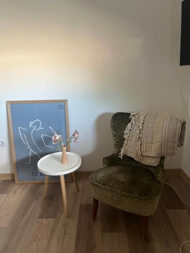 a room with a chair and a table with a vase of flowers at Velora apartments in Subotica