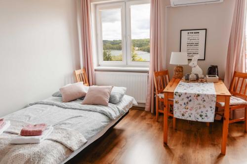 a bedroom with a bed and a desk and a window at Mira - Mira pokoje z widokiem na jezioro in Chmielno