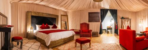 伊尔富德Palais Du Desert Hotel & Spa的一间卧室配有一张大床和红色椅子