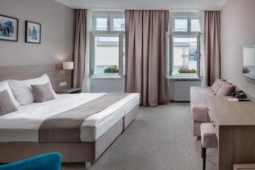 a bedroom with a bed and a couch and windows at Hotel Florenc in Prague