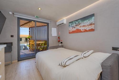 a bedroom with a white bed and a balcony at Fajã Lodges - Studio Ash in São Vicente