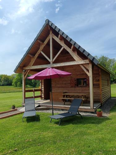 two chairs and an umbrella in front of a cabin at Chalets "Ô Cœur des Puys" in Ceyssat
