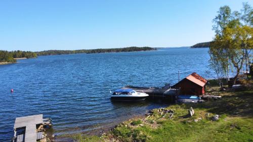 a small boat is docked on the shore of a lake at Hus Skärgården in Figeholm