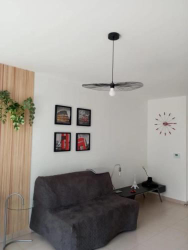 un salon avec un canapé et une horloge au mur dans l'établissement Beach & Golf Cabourg - 50m2 avec jardin clos à 100m golf Cabourg et 200m plage de Cabourg le Home, à Varaville