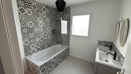 a white bathroom with a tub and a sink at Les maisons Inael in Pénestin
