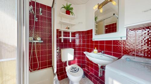 ヘルヌムにあるHickory Hideawayの赤いタイル張りのバスルーム(洗面台、トイレ付)