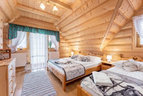 two beds in a room with a wooden ceiling at Domki i Apartamenty Krupa Ciche z Jacuzzi in Zakopane