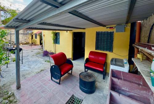 a patio with two red chairs and awning at Hostal Inn & Apartamentos Sol & Luna in Flores