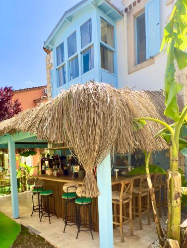 a bar with chairs and a straw umbrella at Banana Alaçatı Food & Stay - Adults Only in Alacati