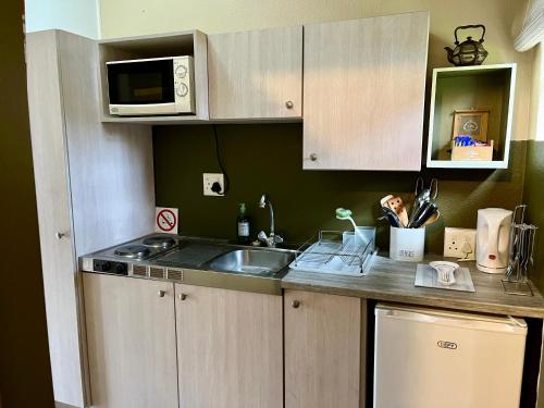 a kitchen with a sink and a microwave at Studio 28 Clarens Apartment B in Clarens