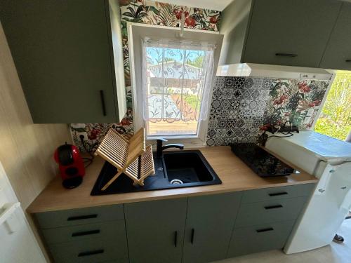 Una pequeña cocina con fregadero y ventana. en Chalet de jardin, piscine, en Seignosse