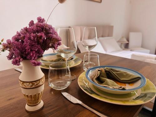 a table with two plates and a vase with purple flowers at Dimora Iryna in Monopoli
