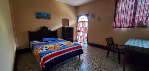 a bedroom with a bed and a table and a window at Casa Guillermo Batz in San Pedro La Laguna
