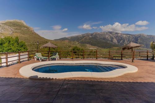 a swimming pool with a table and chairs and a mountain at Casa Chely in Alcaucín