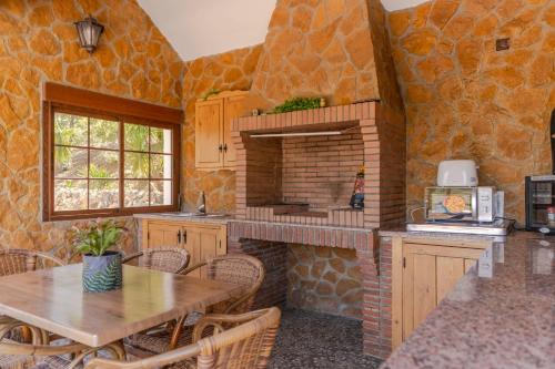 a kitchen with a table and a brick fireplace at Casa Chely in Alcaucín
