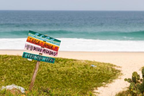 a sign on a beach with the ocean in the background at SA · Beachfront Saquarema: Your beach house! in Saquarema