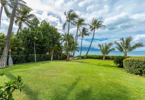 a large yard with palm trees and the ocean at Maalaea Banyans 102 by Coldwell Banker Island Vacations in Wailuku