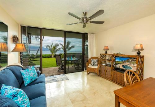 a living room with a blue couch and a ceiling fan at Maalaea Banyans 102 by Coldwell Banker Island Vacations in Wailuku