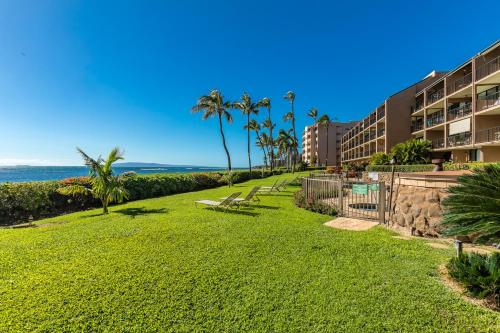 a park next to a resort with palm trees and the ocean at Maalaea Banyans 102 by Coldwell Banker Island Vacations in Wailuku