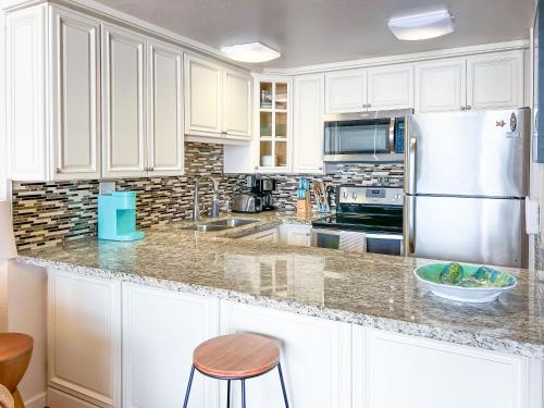 a kitchen with white cabinets and a stainless steel refrigerator at Maalaea Kai 215 by Coldwell Banker Island Vacations in Wailuku