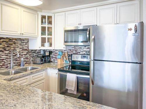 a kitchen with white cabinets and a stainless steel refrigerator at Maalaea Kai 215 by Coldwell Banker Island Vacations in Wailuku