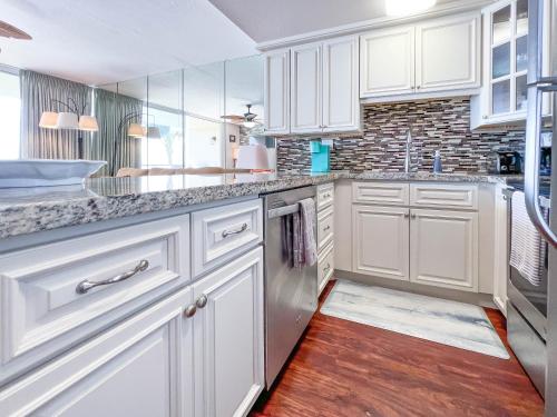 a kitchen with white cabinets and a wooden floor at Maalaea Kai 215 by Coldwell Banker Island Vacations in Wailuku