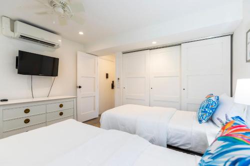 two white beds in a bedroom with a tv at Maalaea Banyans 416 by Coldwell Banker Island Vacations in Wailuku