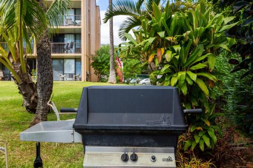 a barbecue grill in a yard with a building at Maalaea Banyans 416 by Coldwell Banker Island Vacations in Wailuku