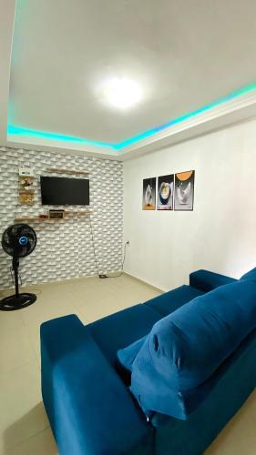 a blue couch in a living room with a tv at Aconchego Praia da Concha, Ilhéus - BA in Ilhéus