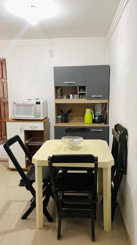 a table and chairs in a kitchen with a microwave at Aconchego Praia da Concha, Ilhéus - BA in Ilhéus