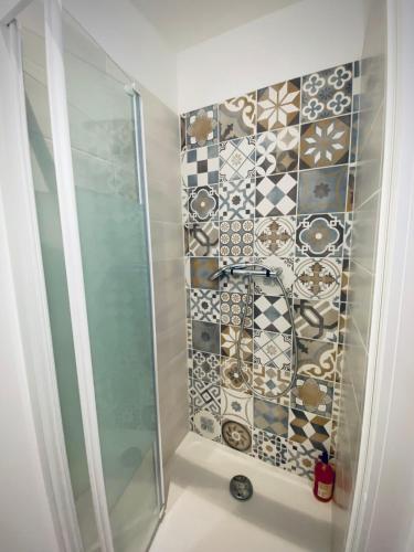 La salle de bains est pourvue d'une douche et d'un mur en mosaïque. dans l'établissement Au Bords des Embruns 4 personnes, à Grandcamp-Maisy