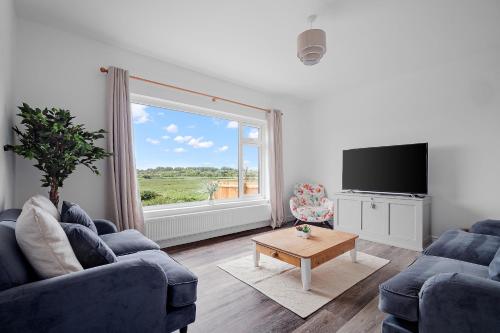 a living room with two blue couches and a large window at Bay View Luxury Stays - Southdown in Overcombe