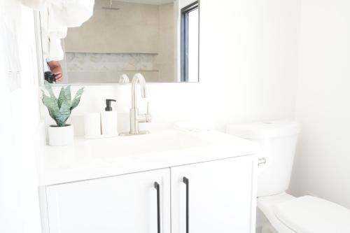 a white bathroom with a sink and a mirror at Koastal Cove 4beds-3baths 2-kingbeds in Deerfield Beach