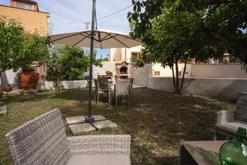 a table and chairs with an umbrella in a yard at Alessandra's apartment in Sassari