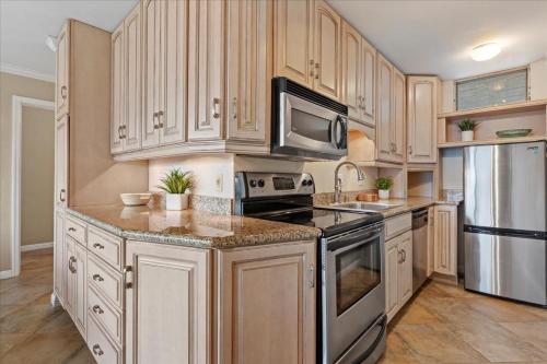 a kitchen with wooden cabinets and stainless steel appliances at Nani Kai Hale 604 by Coldwell Banker Island Vacations in Kihei