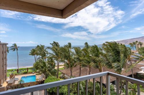 a balcony with a view of the ocean and palm trees at Nani Kai Hale 604 by Coldwell Banker Island Vacations in Kihei