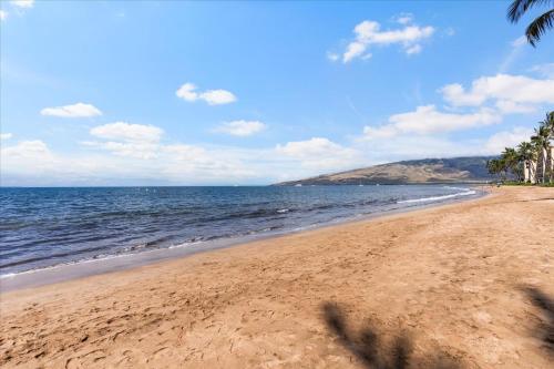 a sandy beach with palm trees and the ocean at Nani Kai Hale 604 by Coldwell Banker Island Vacations in Kihei