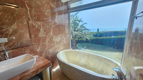 un bagno con vasca, lavandino e finestra di Villa Con Piscina El Mirador de Peñiscola a Peñíscola