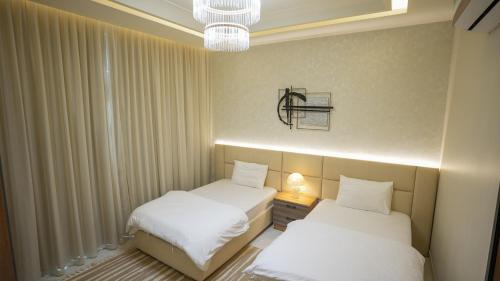 two twin beds in a room with white curtains at مجمع شاليهات هيلز in Salalah