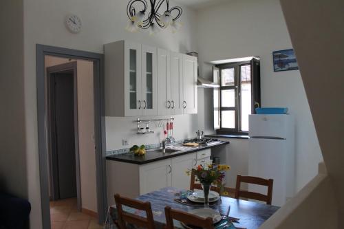 a kitchen with white cabinets and a table with flowers on it at Casa Marietta in Lipari