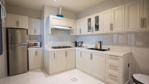 a kitchen with white cabinets and a stainless steel refrigerator at مجمع شاليهات هيلز in Salalah