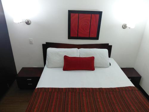 a bedroom with a bed with a red pillow on it at HBCF Hotel Boutique Casa Farallones de Santiago de Cali in Cali