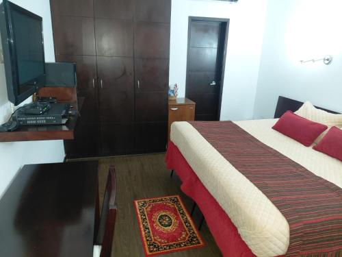 a bedroom with a bed and a desk and a television at HBCF Hotel Boutique Casa Farallones de Santiago de Cali in Cali