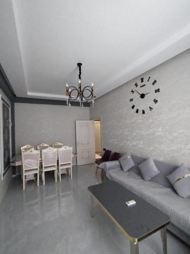 a living room with a couch and a clock on the wall at Sumqayıt Abşeron City yaşayış kompleksi in Sumqayyt