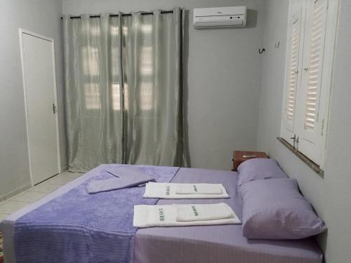 a bedroom with a purple bed with two towels on it at Casa Verde Marinho - Sossego no Jacarecanga in Fortaleza
