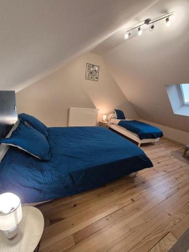 - une chambre mansardée avec un grand lit bleu dans l'établissement Gite le petit Ely, à Thiézac