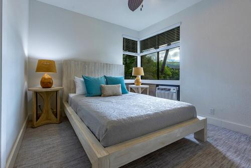 a bedroom with a bed with blue pillows and a window at Grand Champions 166 by Coldwell Banker Island Vacations in Wailea