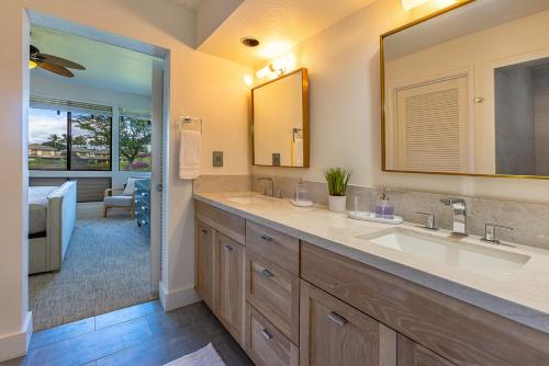 a bathroom with two sinks and a large mirror at Grand Champions 166 by Coldwell Banker Island Vacations in Wailea