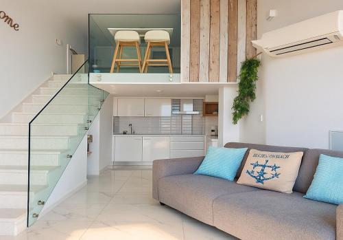 a living room with a couch and a staircase at Luxury Catalan Bay Beach House - Sea + Rock Views in Gibraltar